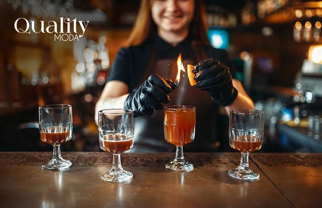 Mujer frente a una barra preparando varias copas de bebidas