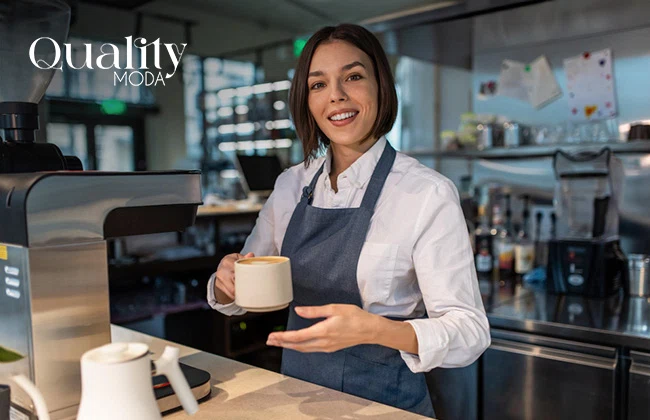 Mujer con delantal con una taza de café servida en su mano derecha